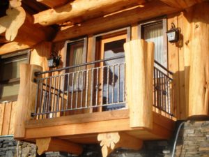 A balcony railing of a log house. The railing has a hammered texture