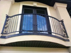 A decorative curved balcony railing with hammered pickets and curled accents on both ends.