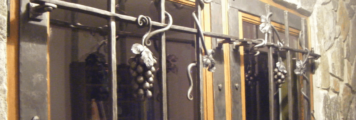 Wine Cellar Door Accents Double wine cellar doors with hammered bars. Vines wrapped around the bars and grapes hang.