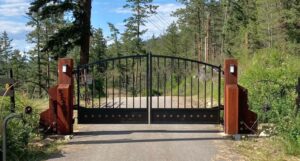 Arched black driveway gate with diamond shaped accents in a rubbed copper finish.