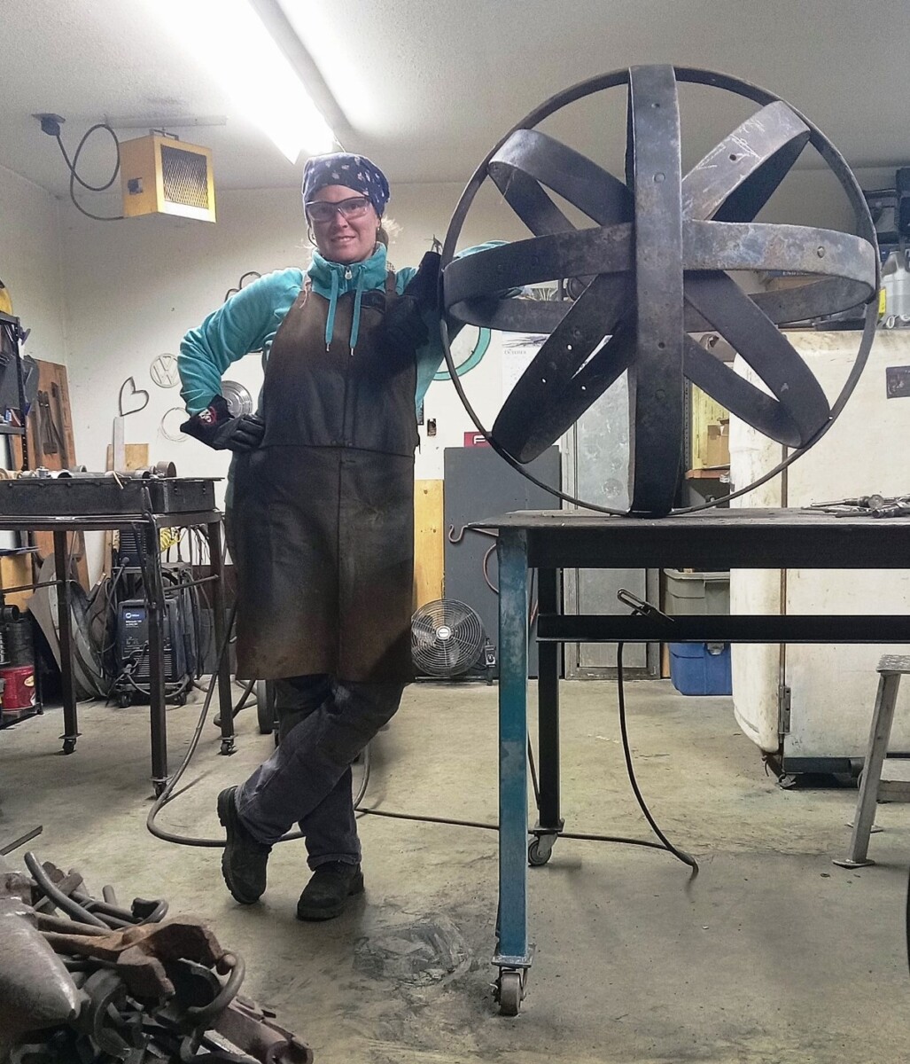 Lisa leaning against a three foot metal sphere, that she created